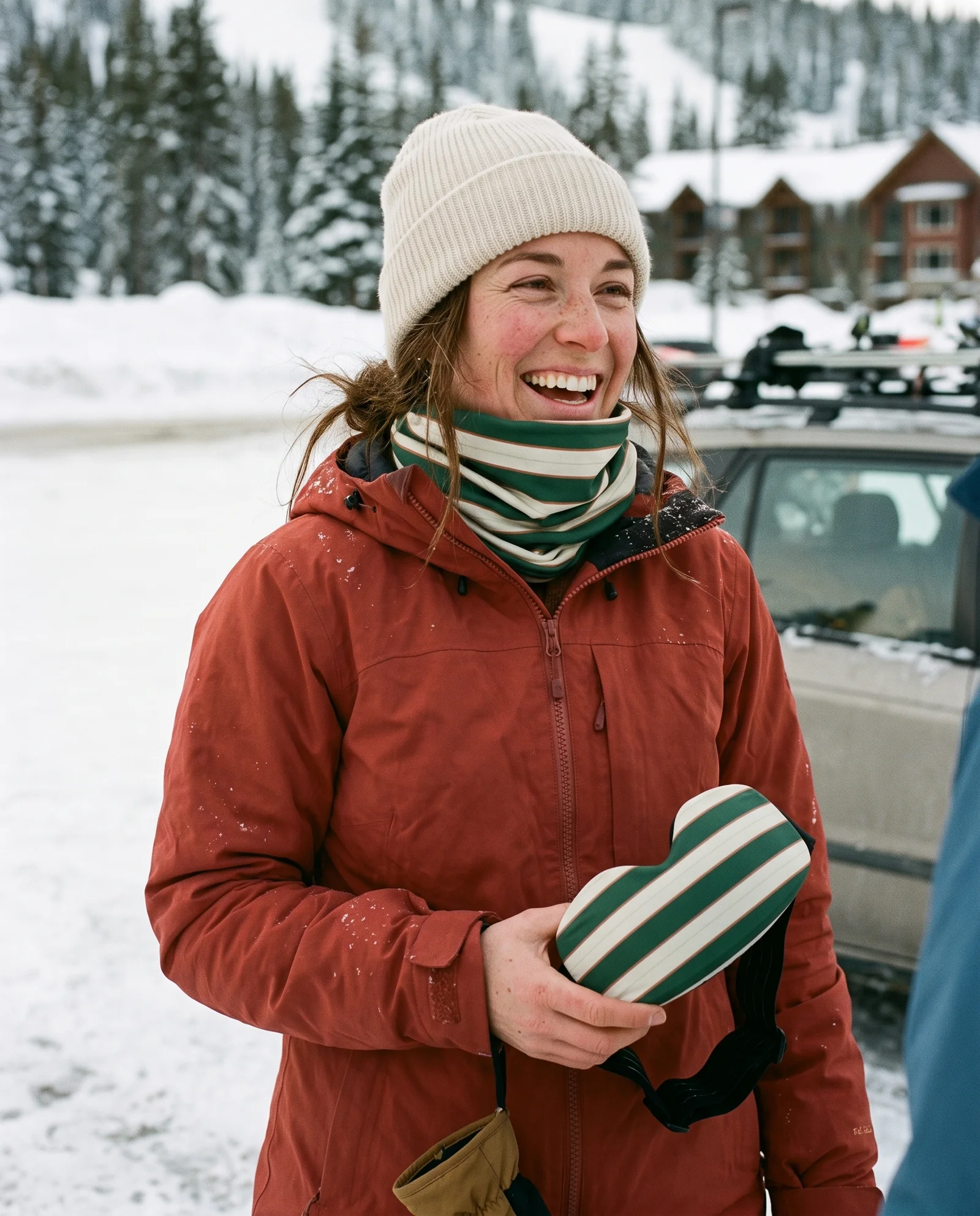 Wintersporter na een afdaling met groene nekwarmer en skibrilhoes in de hand